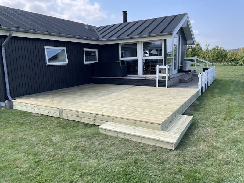 En komplet færdigbygget træterrasse med præcise udskæringer og en jævn overflade, der skaber en flot sammenhæng mellem boligen og haven